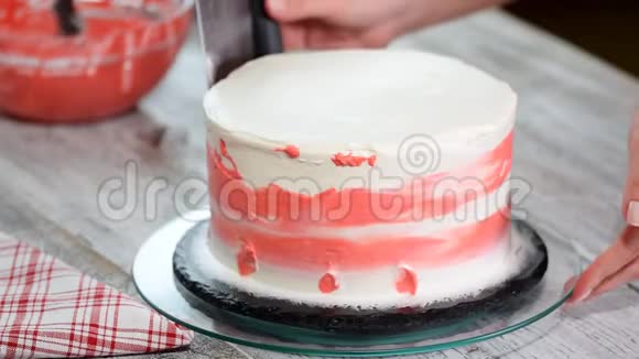 甜点手抹粉红色奶油白色糖霜海绵蛋糕在木制转盘在面包店厨房关闭视频的预览图