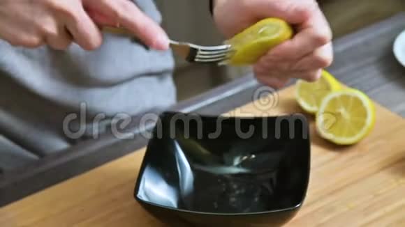 特写女孩用叉子挤用柠檬在黑碗里做酱汁视频的预览图