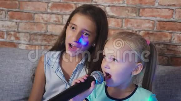 两个小女孩正对着麦克风唱歌家里卡拉OK里的歌4k慢镜头特写视频的预览图
