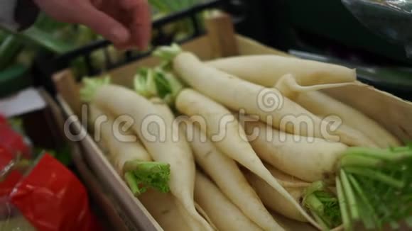 手拿着一个白萝卜在当地超市一个男人买萝卜戴康健康食品视频的预览图