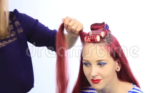女造型师为年轻的红头发妇女创造了一个大卷发的完美发型视频的预览图