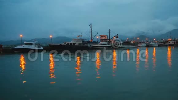 停泊在码头附近的摩托艇夜间灯光照在水面上视频的预览图