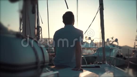 一个英俊的男人在日落时带着游艇看海湾视频的预览图