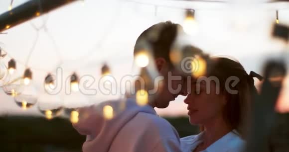 浪漫的肖像快乐的Beautfiul夫妇微笑和摩擦鼻子附近的灯串4K录像视频的预览图