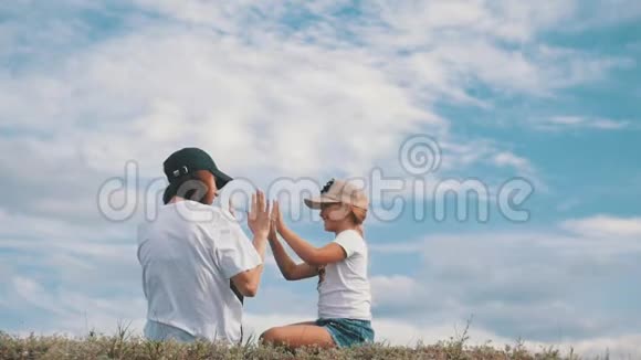一家人在草地上举起手梦想着幸福的家庭观念生活方式自由视频的预览图