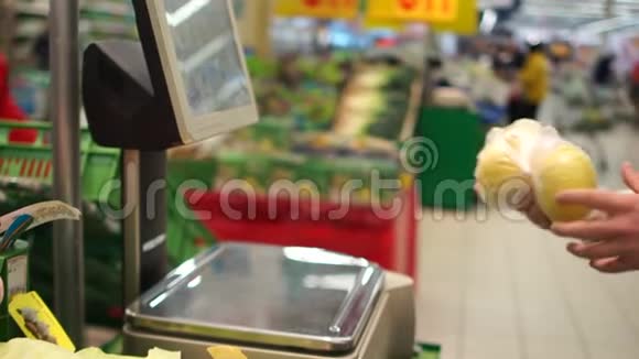 一个认不出来的人用塑料袋在秤上称柠檬的重量自助超市视频的预览图