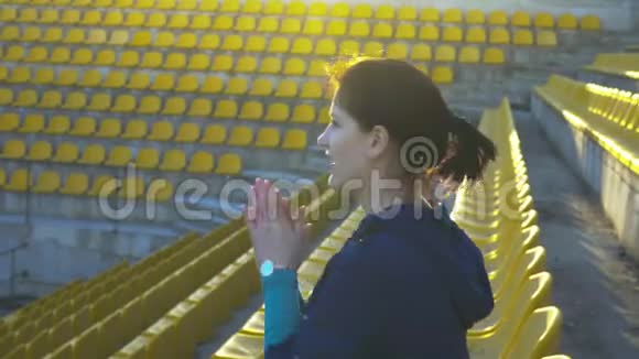一个女孩坐在体育场的看台上4K视频的预览图