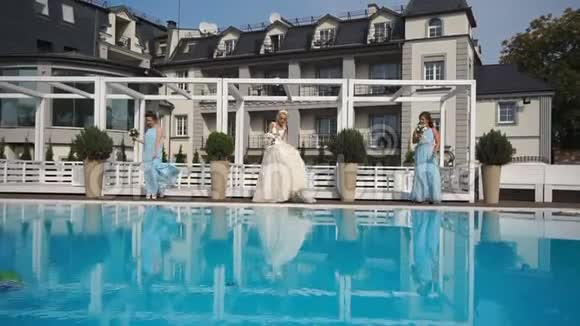 迷人的年轻新娘正和她的女性朋友在豪华游泳池附近跳舞时玩得很开心结婚纪念日视频的预览图