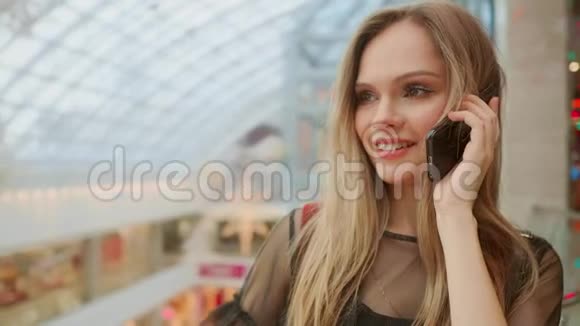 美丽的女孩在智能手机上聊天坐着购物中心的购物袋视频的预览图