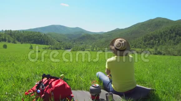 那个带着红色背包的旅行者的女人看着山煤气炉上的茶壶站在附近视频的预览图