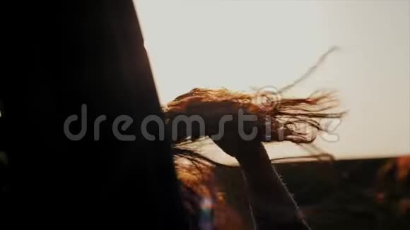 一个留着长发的女孩骑着一辆车的后特写她的头发随风飘动她的手在车外视频的预览图