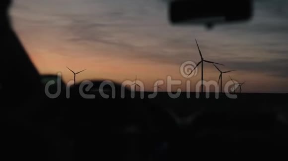 傍晚时分开车经过一片广阔的田野上面有风车视频的预览图