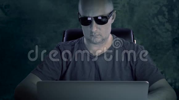 一个穿T恤和眼镜的年轻人坐在电脑前一个男人在深夜在电脑上工作视频的预览图