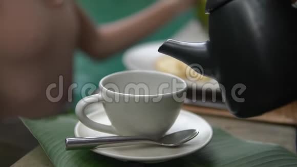 在大白杯中用黑水壶倒出的慢动作茶视频的预览图