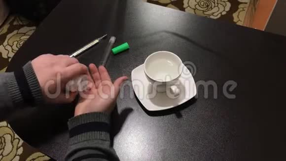 那个人坐在桌子旁从一罐药丸里拿出来的他喝了一杯水接下来是一个热金属视频的预览图