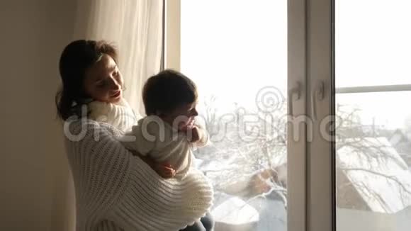 冬天妈妈和儿子坐在房子的大窗户上视频的预览图