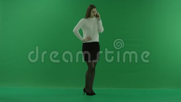女孩站在半个转弯处看着右边在电话里说话在绿色的屏幕上积极地打手势视频的预览图