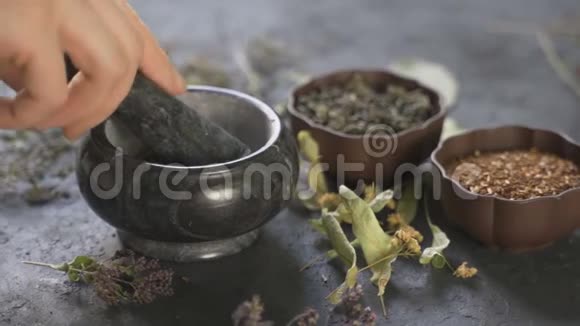药材配制使用餐桌上的药用植物女人用灰泥揉药用植物视频的预览图