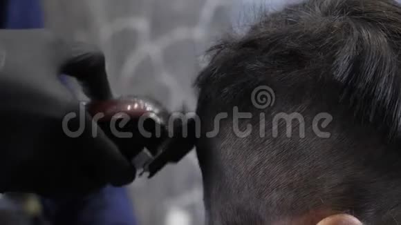 戴着黑手套的理发师把孩子剃成关闭60英尺高视频的预览图
