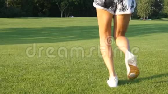 在阳光和风中运动女孩在草地上奔跑的腿背视频的预览图