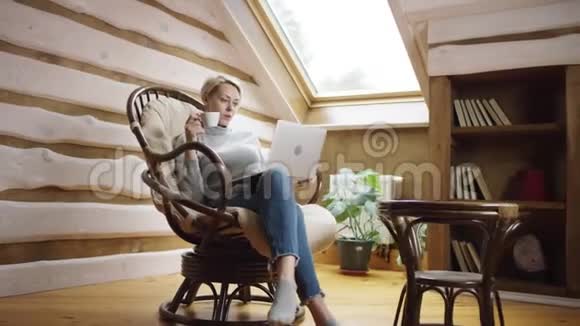 金发女人一边喝咖啡一边用笔记本电脑视频的预览图