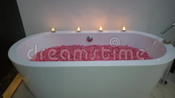 带花瓣的温泉浴盆侧面拍摄白色的浴盆用蜡烛装饰视频的预览图