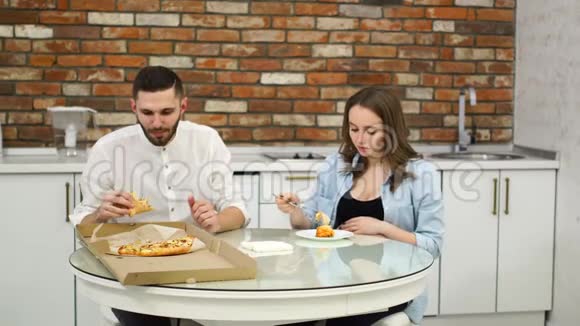 男人和孕妇在家里厨房里吃披萨糟糕的饮食油腻的食物肥胖视频的预览图