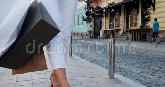 快乐微笑美丽年轻的女人在销售期间带着购物穿过城市视频的预览图
