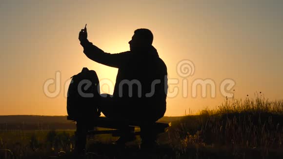 一个带背包的年轻游客用手机拍照在夕阳下旅行概念视频的预览图
