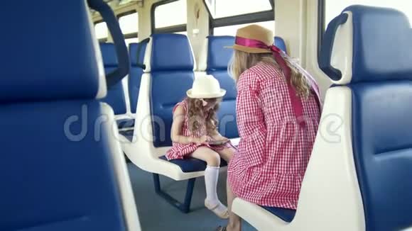 小女孩用智能手机坐在火车上她妈妈的前面视频的预览图