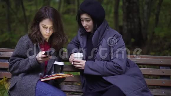 公园里有两个带智能手机的年轻美女视频的预览图