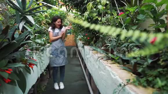 在温室里围着围裙的女孩因花粉植物而发痒对花过敏视频的预览图