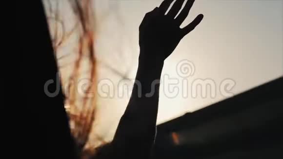 一位女性坐在车上把手伸出窗外她的头发在翅膀上飞扬近距离观察后视图视频的预览图