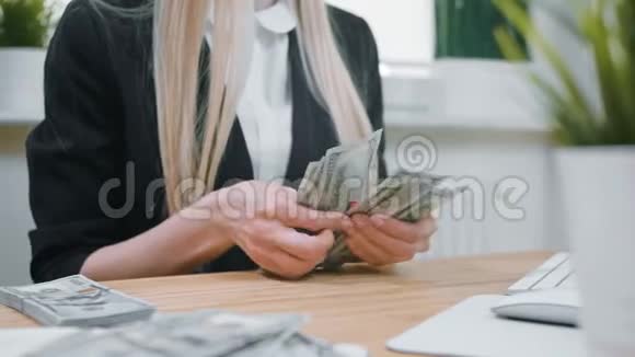 女商人手里拿着现金女性穿着优雅的西装坐在木桌旁数着大桌子视频的预览图
