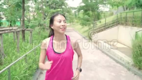 慢动作健康美丽的年轻亚洲跑步妇女穿运动服装在城市公园的街道上跑步和慢跑视频的预览图