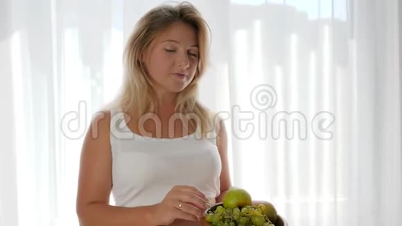 裸露大肚子的女性吃葡萄靠窗吃水果营养健康视频的预览图