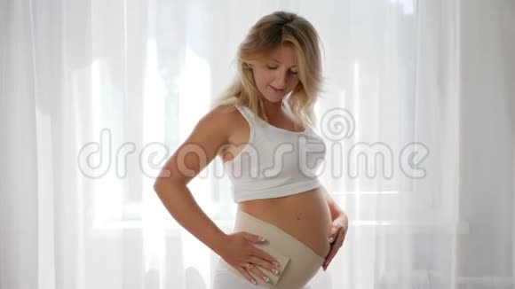 为孕妇提供舒适的舒适而用绷带在摄像机上摆姿势的女孩特写镜头视频的预览图