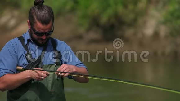 渔夫拿着一根鱼竿在河上钓鱼站在水里视频的预览图