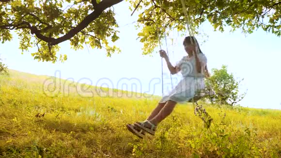 一个长发少女在橡树下的秋千上荡秋千视频的预览图