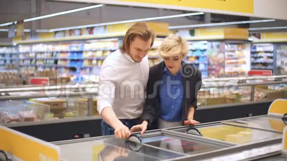 销售消费主义和人的观念幸福的夫妻与购物车购买冷冻食品在杂货店或视频的预览图