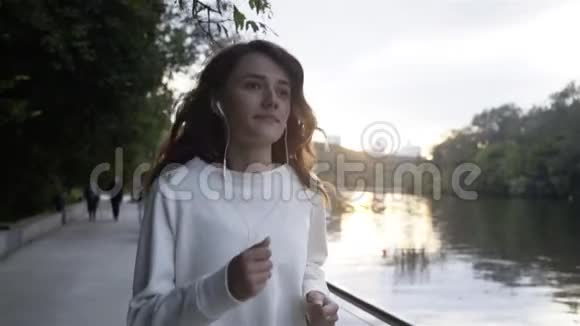 穿白色衣服在河边慢跑的年轻女子视频的预览图