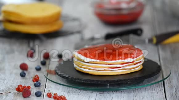 女性糕点厨师用旋转蛋糕制作美味的海绵蛋糕鲜奶油和浆果果酱视频的预览图