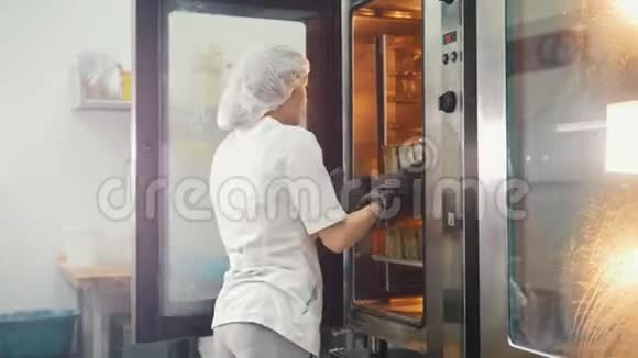 商业厨房里的女性烤饼从烤箱里拿出面包视频的预览图