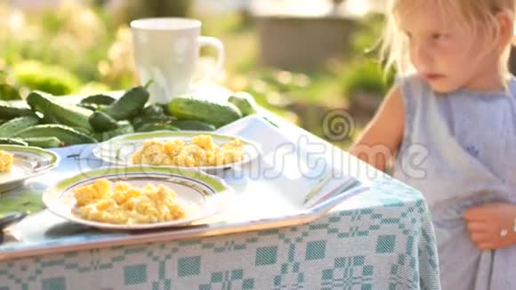 一个小女孩带着新鲜的黄瓜吃晚饭从口袋里拿出它们到桌子上夏季新鲜空气视频的预览图