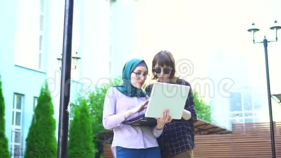 戴头巾的穆斯林女孩和她的朋友很高兴看到笔记本电脑视频的预览图