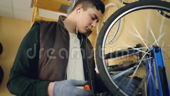 专心的机械师在修理自行车和听音乐的同时用特殊工具将辐条固定在自行车轮上视频的预览图