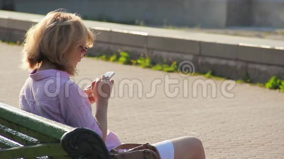 女士微笑着在智能手机上阅读信息浏览互联网视频的预览图