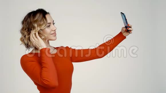 微笑的女人在智能手机上拍摄自我肖像灰色背景视频的预览图