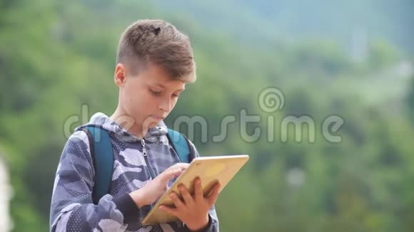 可爱的聪明男孩有平板电脑手里拿着平板电脑在户外平板电脑小学教育新技术视频的预览图