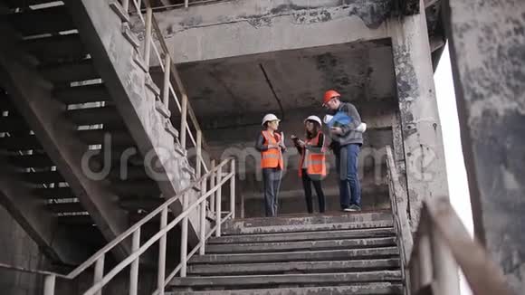 工程师和两名女检查员在现场施工或恢复现场检查楼梯间并讨论有关细节视频的预览图
